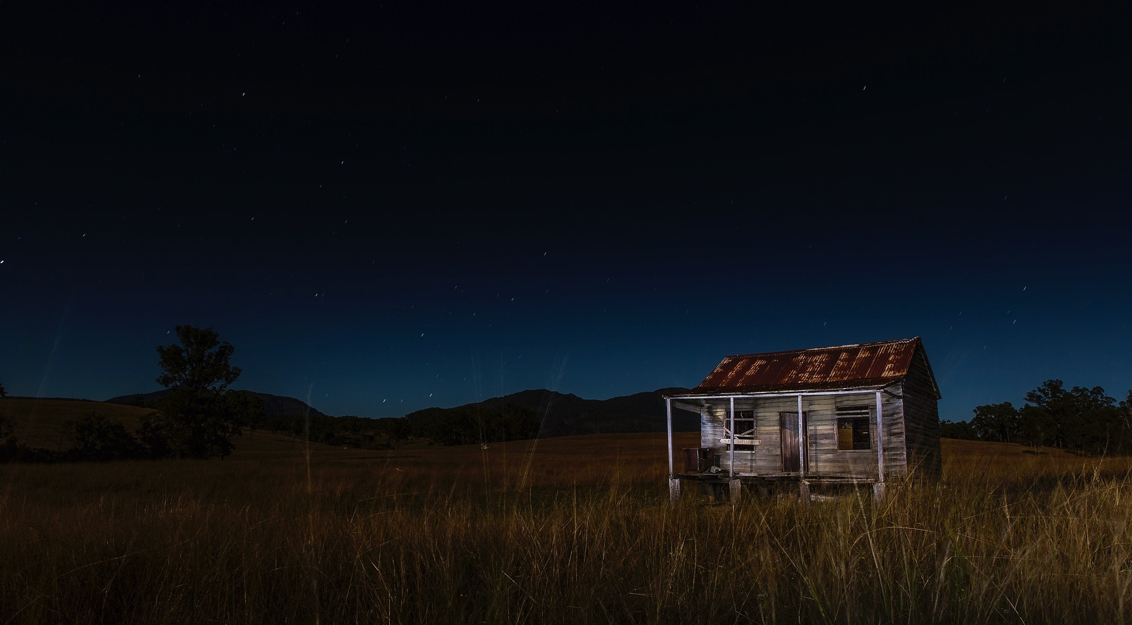 rustic cabin in field at night